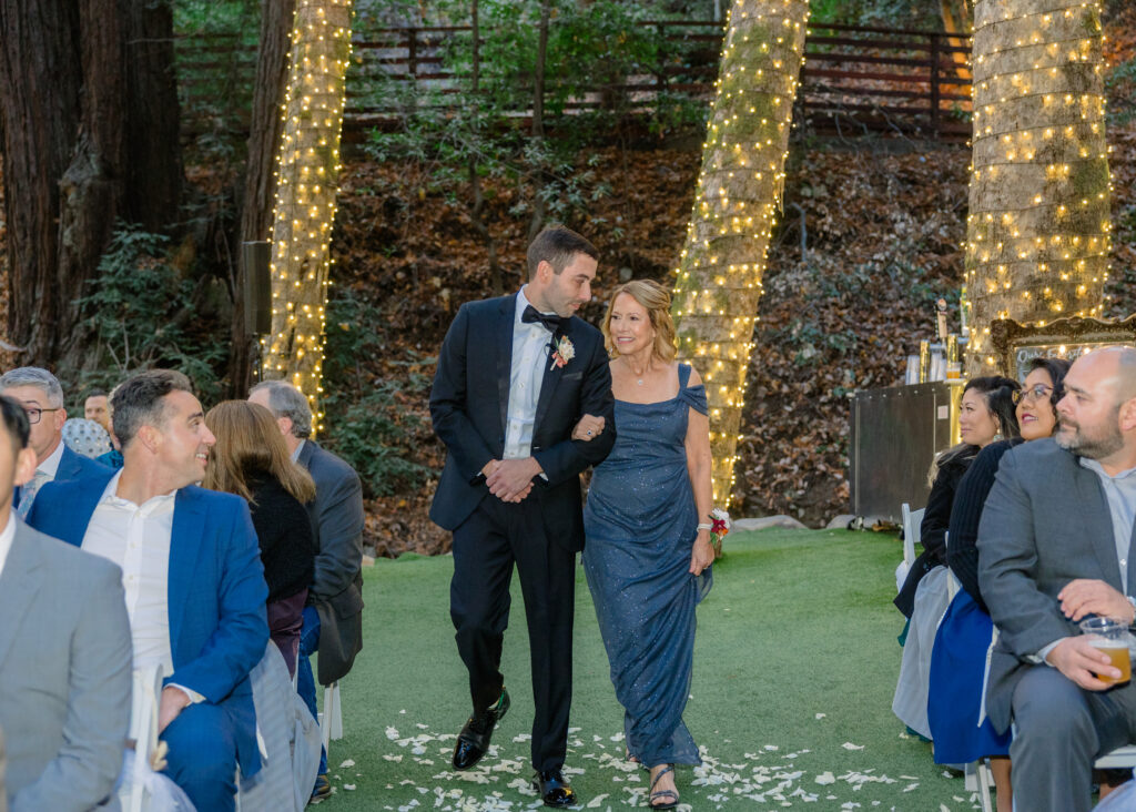 A groom walks down the aisle with his mother at a Saratoga Springs Wedding