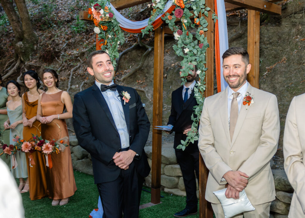 A groom smiles at the alter.