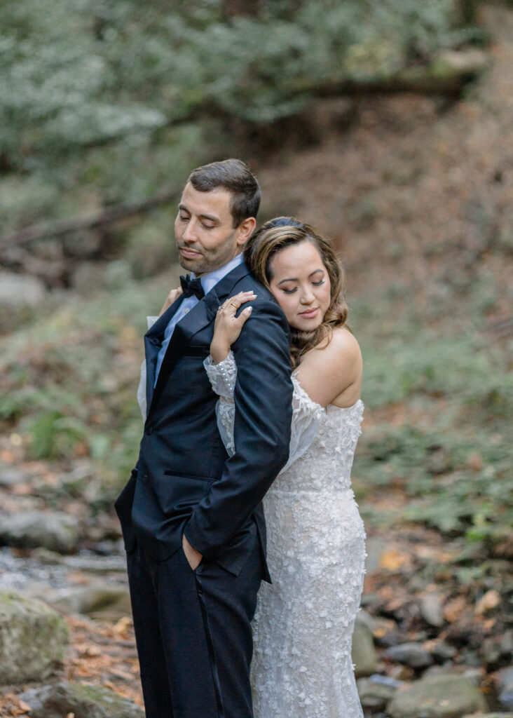 A bride hugs the back of a groom. 